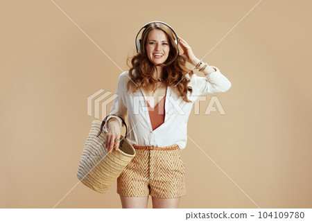 smiling stylish woman in blouse and shorts on beige smiling stylish woman in blouse and shorts on beige 104109780