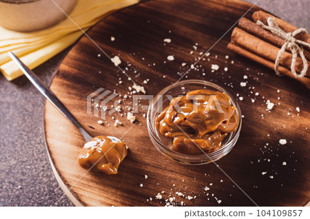 Boiled condensed milk in glass bowl and a can on the table 104109857