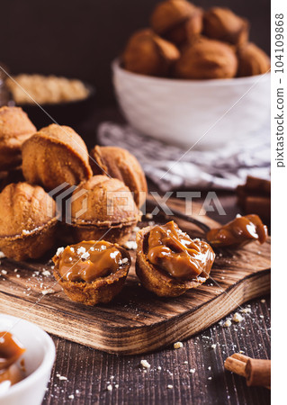 Homemade walnut shaped cookies filled with boiled condensed milk on a board vertical view Homemade walnut shaped cookies filled with boiled condensed milk on a board vertical view 104109868