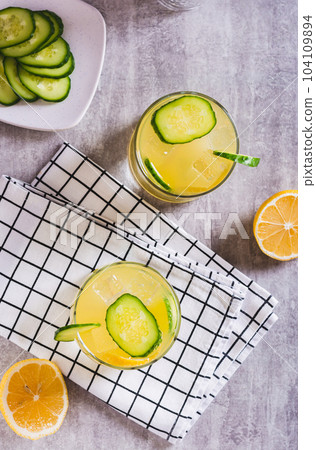 Detox summer lemonade with lemon and cucumber in glasses on the table top and vertical view Detox summer lemonade with lemon and cucumber in glasses on the table top and vertical view 104109894