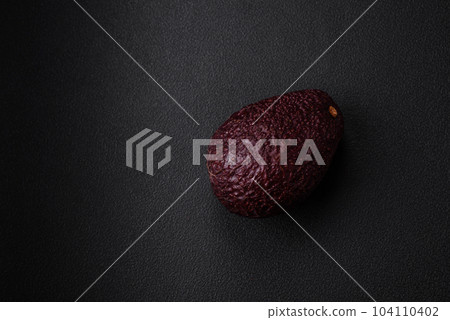 Fresh, ripe, soft brown colored avocado on a dark concrete background 104110402