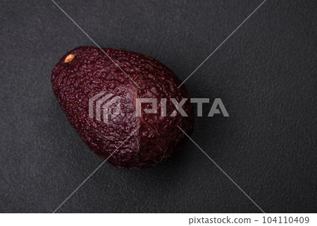 Fresh, ripe, soft brown colored avocado on a dark concrete background 104110409