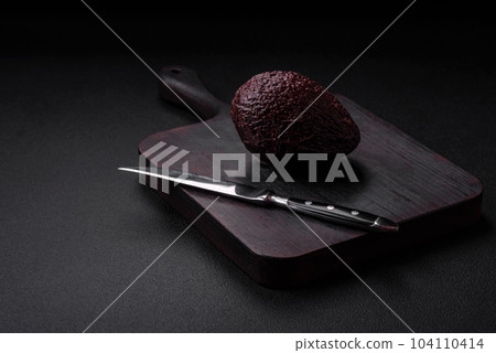 Fresh, ripe, soft brown colored avocado on a dark concrete background 104110414