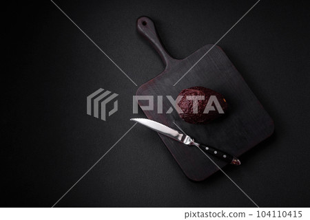 Fresh, ripe, soft brown colored avocado on a dark concrete background 104110415
