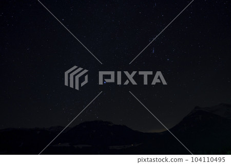 Idyllic shot of stars glowing over silhouette mountain and landscape at night 104110495