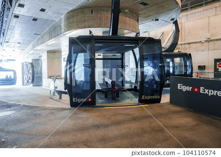 Gondola lift with empty seats and eiger express text on open doors inside modern Grindelwald terminal at Jungfrau, Switzerland, winter holiday concept for tourists 104110574