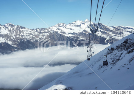 Gondola lifts moving on cables over snow covered hill with beautiful snowcapped Bernese mountains under sky at ski resort in Jungfrau, Switzerland, winter holiday and nature concept Gondola lifts moving on cables over snow covered hill with beautiful snowcapped Bernese mountains under sky at ski resort in Jungfrau, Switzerland, winter holiday and nature concept 104110648