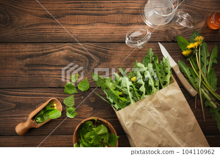 Picked fresh dandelion leaves. Raw Green organic dandelion greens for cooking salad or brewing tea. Bowl of birch leaves for making herbal tea. Healthy eating. Herbal medicine. Top view, flat lay. Picked fresh dandelion leaves. Raw Green organic dandelion greens for cooking salad or brewing tea. Bowl of birch leaves for making herbal tea. Healthy eating. Herbal medicine. Top view, flat lay. 104110962