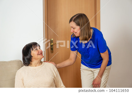 Young caregiver helping senior woman at home. Caring nurse assisting her middle aged female patient. Young caregiver helping senior woman at home. Caring nurse assisting her middle aged female patient. 104111650