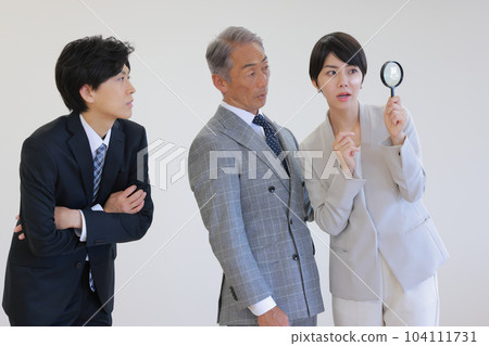 A female executive and two men looking for company policies with a magnifying glass_1 A female executive and two men looking for company policies with a magnifying glass_1 104111731