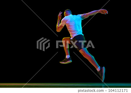Dynamic image of young man with muscular, strong, fit body, professional runner in motion against black studio background in neon light Dynamic image of young man with muscular, strong, fit body, professional runner in motion against black studio background in neon light 104112171
