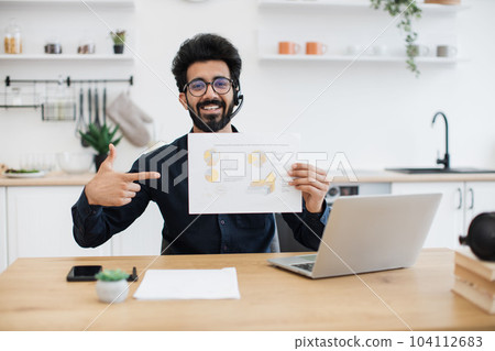 Male in headset posing with infographics in home workplace 104112683