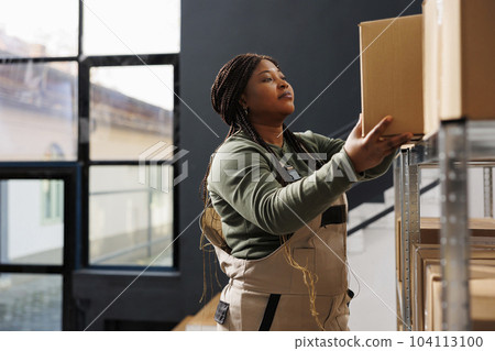 African american employee putting products in carton boxes, preparing customers orders in storehouse. Storage room supervisor working at packages shipping while doing goods quality control African american employee putting products in carton boxes, preparing customers orders in storehouse. Storage room supervisor working at packages shipping while doing goods quality control 104113100