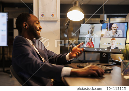 Smiling executive manager having remote conversation with team discussing marketing strategy during online videocall meeting. Diverse coworkers working at company growth report in office 104113125