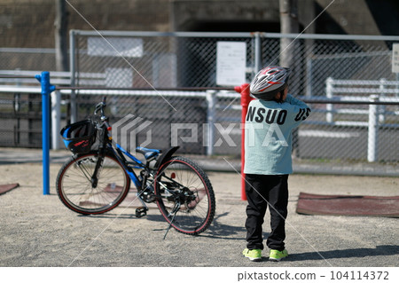 A boy riding a bicycle wearing a helmet properly A boy riding a bicycle wearing a helmet properly 104114372