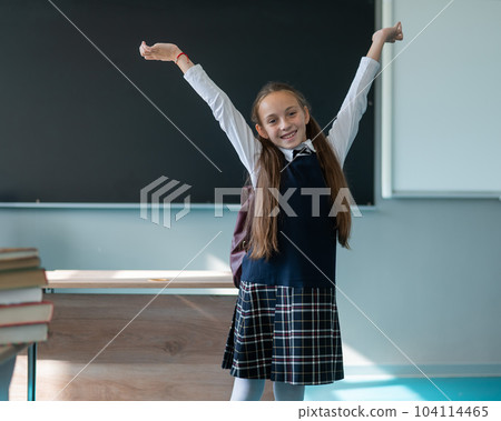 A caucasian girl stands with her arms outstretched at the blackboard. The lessons are over. A caucasian girl stands with her arms outstretched at the blackboard. The lessons are over. 104114465