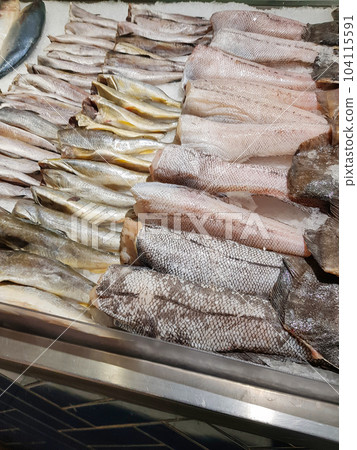 Food background close-up. There are many varieties of fresh fish on the ice lying in a row. Sale of fresh frozen fish at the fish market 104115591