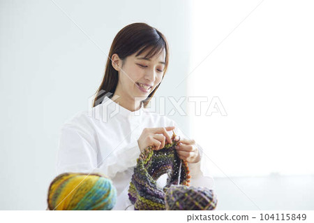 一位女士在家裡的客廳織毛衣。 一位女士在家裡的客廳織毛衣。 104115849
