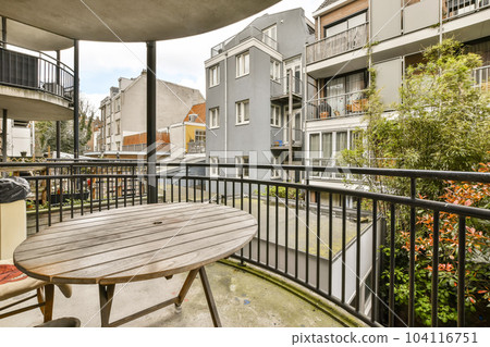 a balcony with chairs, tables and an outdoor table in the fore - image is taken from inside to outside 104116751