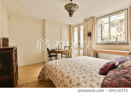 a bedroom with a bed, dresser and window in the back ground is light wood flooring on both sides a bedroom with a bed, dresser and window in the back ground is light wood flooring on both sides 104116755