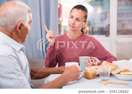 Mature male talking with young sad daughter at table with food Mature male talking with young sad daughter at table with food 104116882