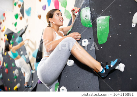 Woman training at bouldering gym without special climbing equipment 104116891