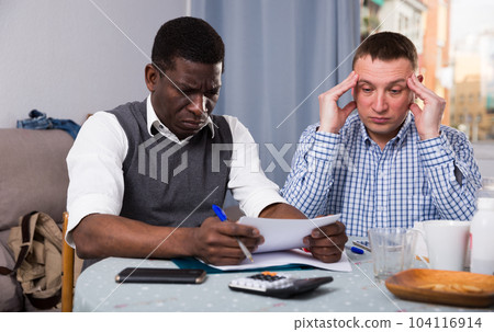 Businessmen with phone in home filling up documents Businessmen with phone in home filling up documents 104116914