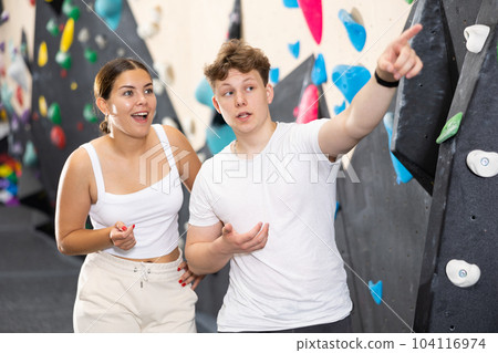 Young woman and teen guy posing near climbing wall 104116974