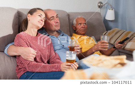 Elderly man with adult children sitting on sofa an watching tv 104117011