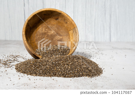 Chia seeds fall from wooden bowl. Healthy superfood rich in Omega 3 fatty acids. Dry healthy natural ingredient. Chia grains are falling Chia seeds fall from wooden bowl. Healthy superfood rich in Omega 3 fatty acids. Dry healthy natural ingredient. Chia grains are falling 104117087