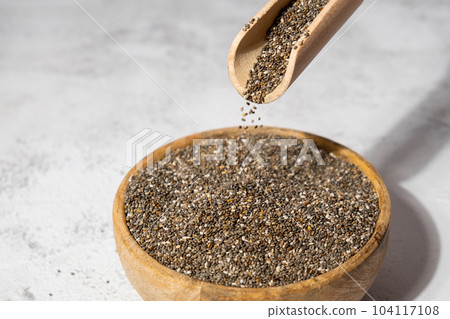 Chia seeds fall in wooden bowl. Healthy superfood rich in Omega 3 fatty acids. Dry healthy natural ingredient. Chia grains are falling Chia seeds fall in wooden bowl. Healthy superfood rich in Omega 3 fatty acids. Dry healthy natural ingredient. Chia grains are falling 104117108