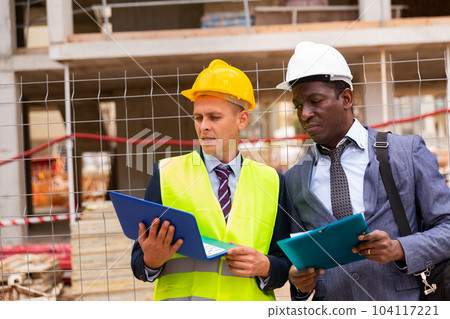 African-american architect and an engineer controlling the progress of work holding a laptop African-american architect and an engineer controlling the progress of work holding a laptop 104117221