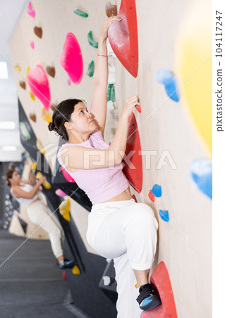 Young asian woman practicing rock climbing on climbing wall 104117247