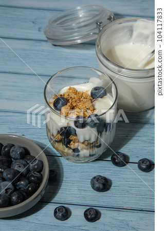 Morning granola breakfast with homemade greek yogurt, blueberries in glasses on blue wooden background. Healthy diet Crunchy granola with yogurt nuts and blueberries Morning granola breakfast with homemade greek yogurt, blueberries in glasses on blue wooden background. Healthy diet Crunchy granola with yogurt nuts and blueberries 104117833