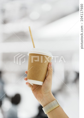 hand holding coffee paper cup, woman drink Tea from disposable cup in cafe shop. Takeaway and free plastics concept 104117980