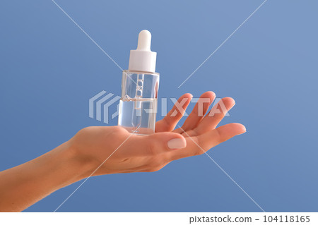 Serum with a pipette in female hands on a blue background. Serum with a pipette in female hands on a blue background. 104118165