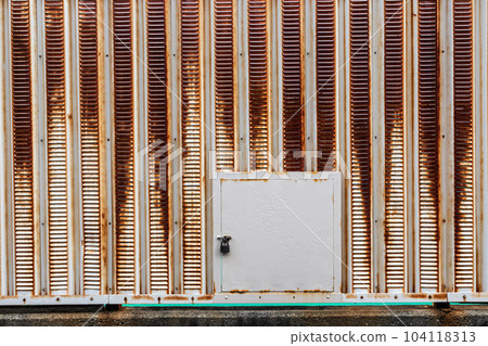 A rusty old iron wall with a small door with a lock A rusty old iron wall with a small door with a lock 104118313