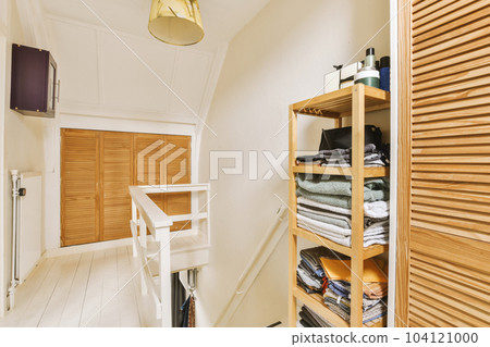 a room with wooden shutters on the wall and white wood flooring in front of the door, there is an open closet a room with wooden shutters on the wall and white wood flooring in front of the door, there is an open closet 104121000