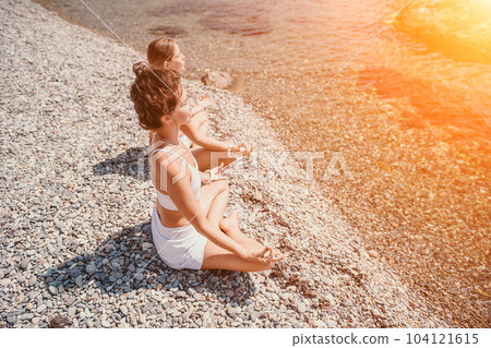 Woman sea yoga. Happy women meditating in yoga pose on the beach, ocean and rock mountains. Motivation and inspirational fit and exercising. Healthy lifestyle outdoors in nature, fitness concept. 104121615