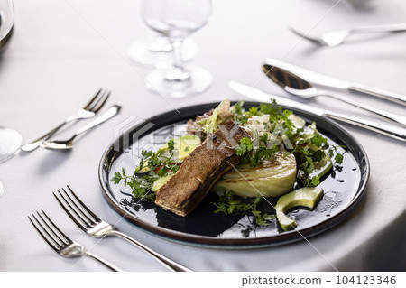 Luxurious table setting with a dark plate full of vegetarian salad with marinated tofu 104123346