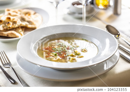 Chicken soup Italian style with small tortellini, carrot, parsley and pizza flatbread Chicken soup Italian style with small tortellini, carrot, parsley and pizza flatbread 104123355