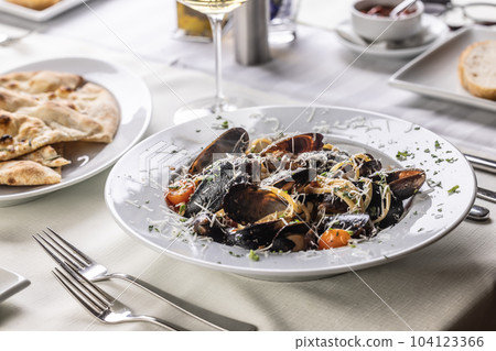Linguine pasta with mussels and grated pecorino cheese on top served in a restaurant Linguine pasta with mussels and grated pecorino cheese on top served in a restaurant 104123366