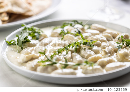 Gnocchi ai quattro formaggi, Italian dough pasta with four types of cheese and ruccola on top 104123369