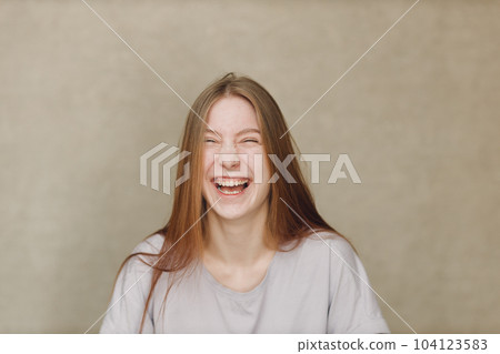 Portrait of young happy laughing caucasian woman at casting movie auditions against beige background 104123583
