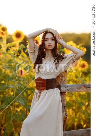 Beautiful woman in a dress in a field of sunflowers Beautiful woman in a dress in a field of sunflowers 104123786
