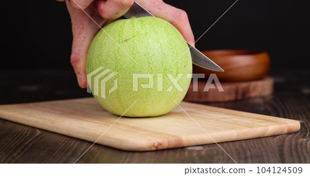Cut an unripe small watermelon on the table 104124509