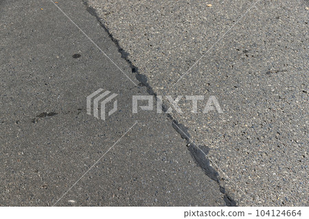The repaired part of an asphalt road with patches 104124664