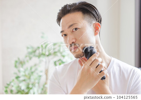 Man shaving with an electric shaver 104125565
