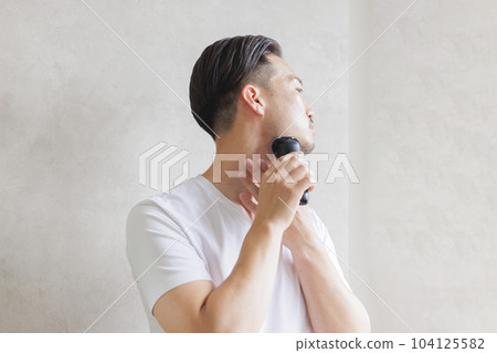Man shaving with an electric shaver 104125582