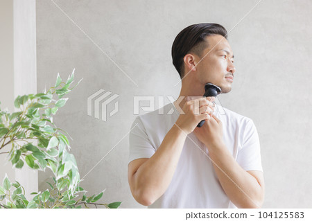 Man shaving with an electric shaver 104125583